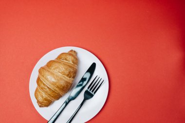 Kırmızı zemin üzerinde kahve olan sabah kruvasanları. 