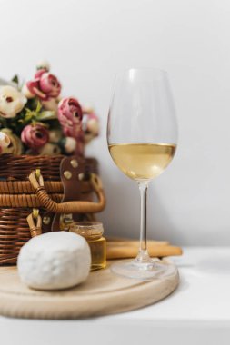 Şarap, peynir ve çiçeklerle dolu beyaz masa.