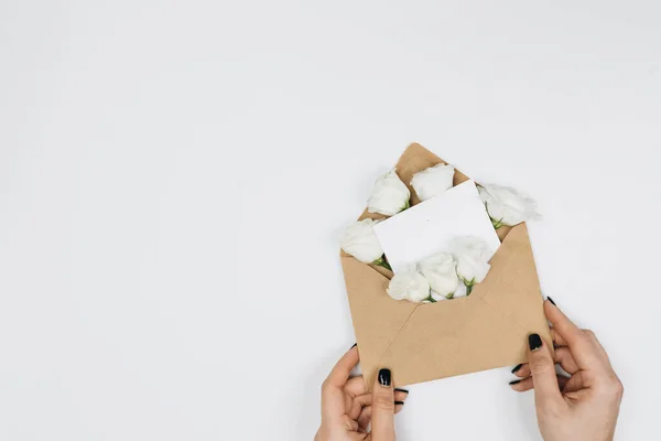 Mãos Femininas Segurando Presente Envelope Com Rosas Brancas — Fotografia de Stock
