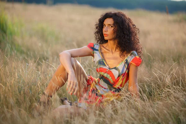 Beautiful brunette woman in a field at sunset — Stock Photo, Image