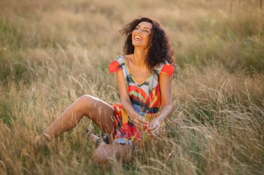 Güzel esmer kadın gün batımında bir tarlada. Mutlu seksi bayan.