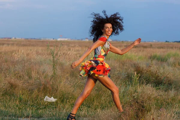 Beautiful brunette woman in a field at sunset — Stock Photo, Image