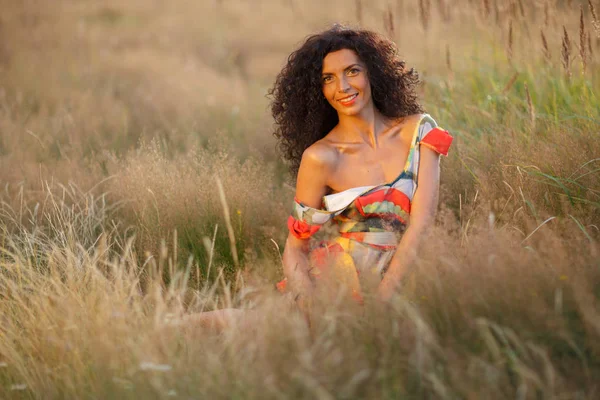 Beautiful brunette woman in a field at sunset — Stock Photo, Image