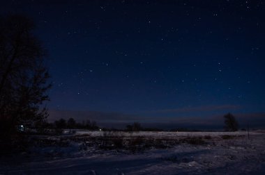 Karla kaplı bir tarlanın üzerindeki yıldızlı gökyüzü.