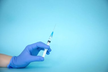 Doktor elinde şırınga tutuyor. İlaç enjeksiyonu. Mavi eldivenli bir tıp çalışanı. Şırıngada aşı. Kozmetik prosedürleri. Hemşire iğneyi yapacak.
