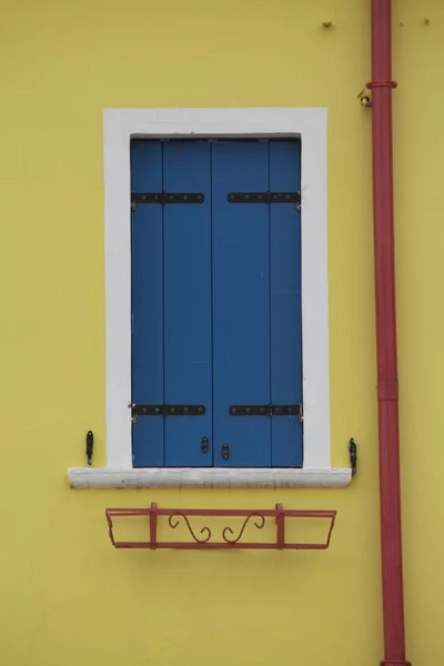 Λαμπρά Χρωματισμένο Τοίχο Κίτρινο Μπλε Παραθυρόφυλλα Και Κόκκινο Αγωγό Σωλήνων — Φωτογραφία Αρχείου
