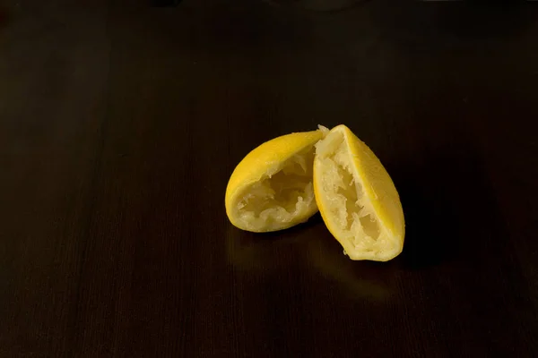 Squeezed lemon skins on dark background - lemon peel