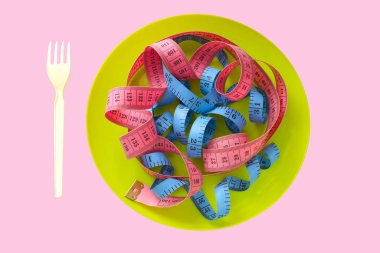 Tabaklardaki renk ölçme bandı, kilo verme konsepti, diyet, sağlıklı yaşam tarzı, pembe arka planda izole edilmiş.