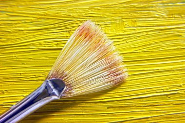 Yağlı boyaların sarı arka planında sanat fırçası, yakın plan.