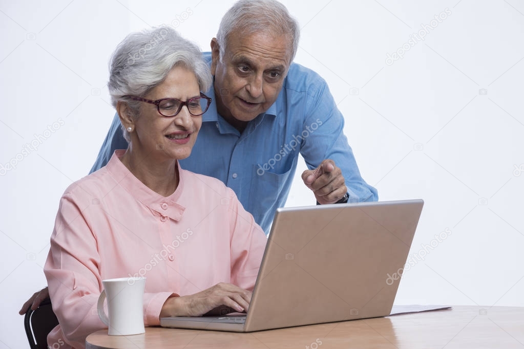 Senior couple looking at laptop and pointing at screen