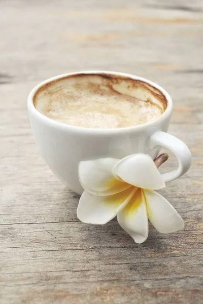 Coffee with milk and white frangipani flower