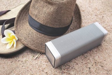 Sahilde şapka ve bluetooth hoparlör ile flip flop