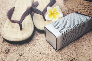 Sahilde şapka ve bluetooth hoparlör ile flip flop