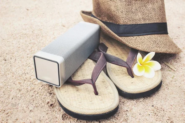 Chanclas con sombrero y altavoz bluetooth en la playa — Foto de Stock