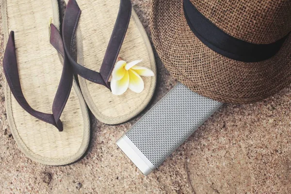 Chanclas con sombrero y altavoz bluetooth en la playa — Foto de Stock