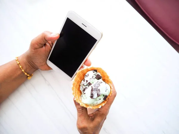 Mujer comiendo helado de menta con teléfono inteligente —  Fotos de Stock