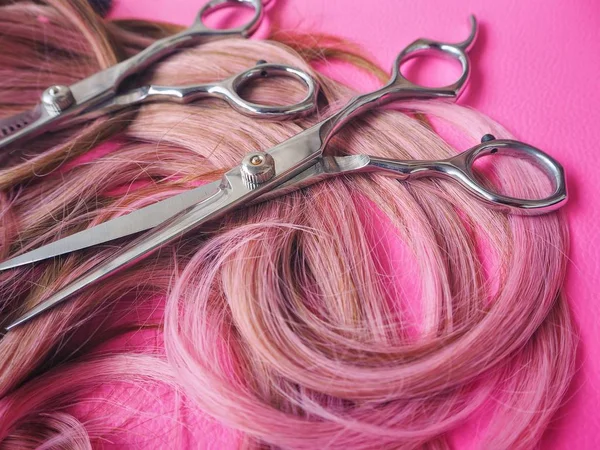 Ножницы для стрижки волос на розовом фоне — стоковое фото