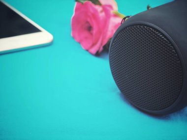 Akıllı telefon ve mavi zemin üzerine gül ile Bluetooth Hoparlör kullanan kadın