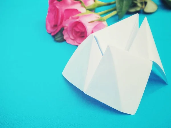 Paper fortune teller and pink rose on blue background