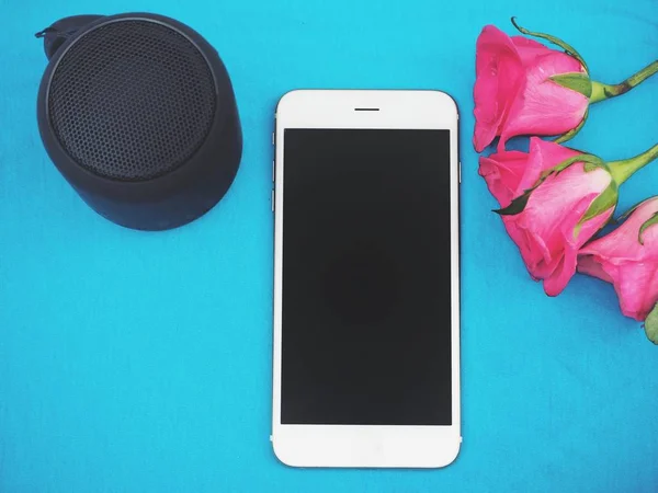 Mujer usando altavoz del bluetooth con el teléfono inteligente y se levantó sobre fondo azul — Foto de Stock