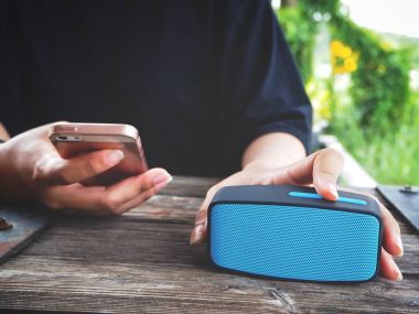Bluetooth hoparlör ile akıllı telefon kullanan kadın
