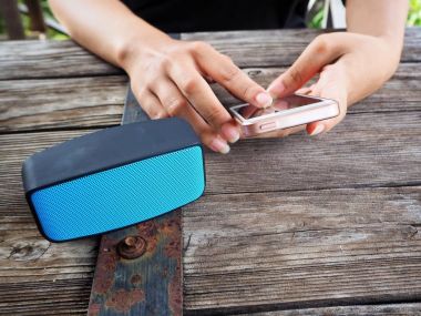 Bluetooth hoparlör ile akıllı telefon kullanan kadın