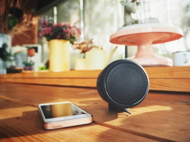 evde masanın üzerinde yatan akıllı telefon ve bluetooth hoparlör