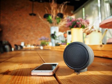 evde masanın üzerinde yatan akıllı telefon ve bluetooth hoparlör