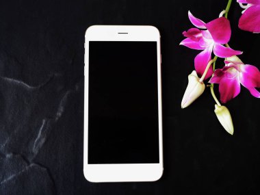 Siyah arka plan üzerine pembe taze orkide çiçekli Beyaz smartphone