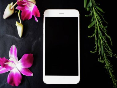 Siyah arka plan üzerine pembe taze orkide çiçekli Beyaz smartphone