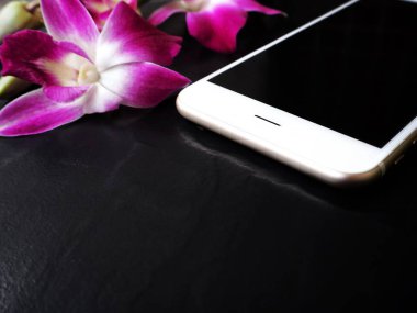 Siyah arka plan üzerine pembe taze orkide çiçekli Beyaz smartphone