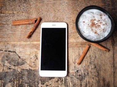 Masa üzerinde krem lezzetli sütlaç ve smartphone ile boş perde üstten görünüm