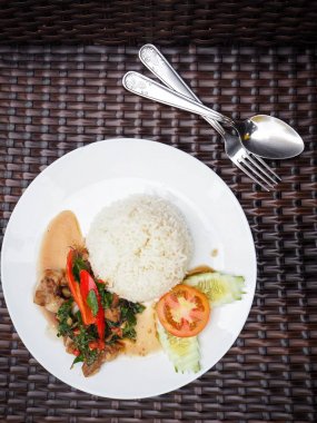 Tay fesleğen domuz eti pilav ve beyaz tabakta sebze ile servis