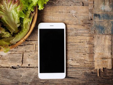 üstten görünüm akıllı telefon boş ekran ve kırmızı marul mutfak ahşap tablo