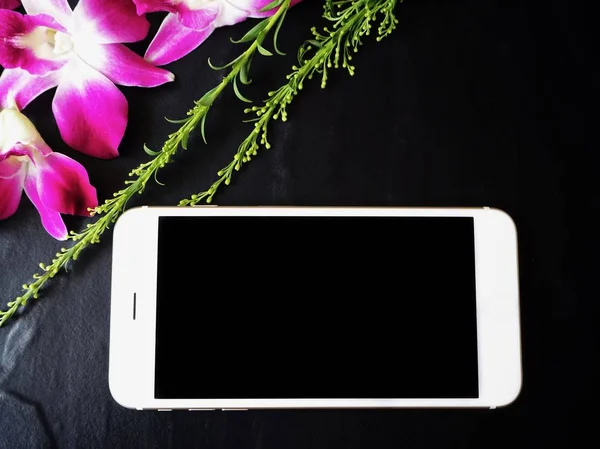 Siyah arka plan üzerine pembe taze orkide çiçekli Beyaz smartphone