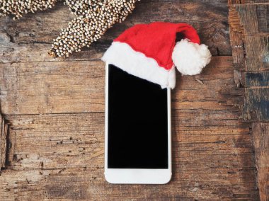 boş ekran ve Noel şapka ile smartphone üstten görünüm ahşap tablo
