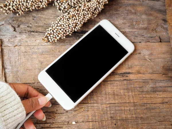 El ve smartphone boş ekran üzerinde ahşap masa şarj ile kısmi üstten görünüm