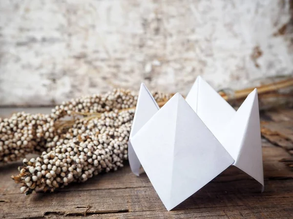 Paper fortune teller with dried flowers on wooden background