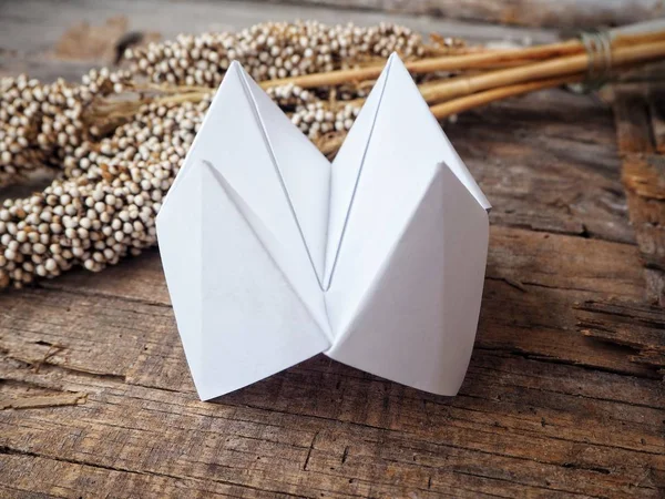 Paper fortune teller with dried flowers on wooden background