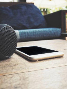arka koltukta ile evde masanın üzerinde yatan akıllı telefon ve bluetooth hoparlör
