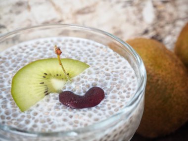 Ahşap arka plan üzerinde Chia tohum pudingle kivi ve kiraz görünümü Kapat