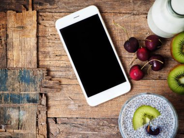 Chia tohum puding ve eski ahşap arka plan üstünde smartphone