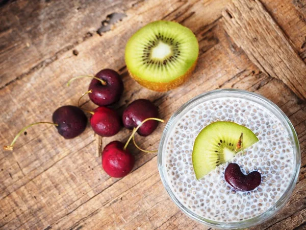 Chia seeds pudding with kiwi and cherries on old wooden background