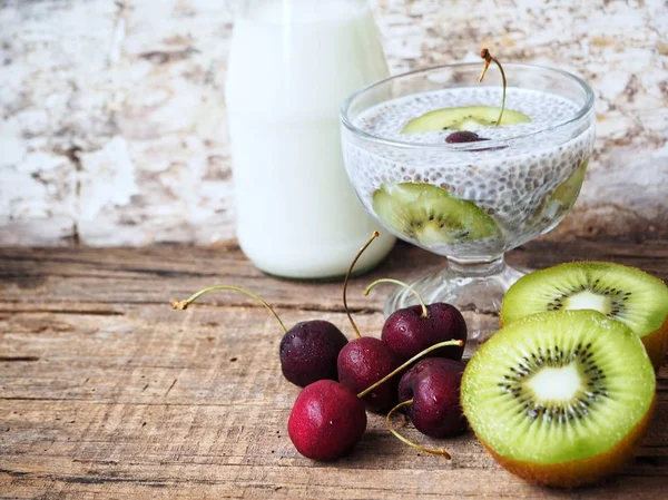 Chia seeds pudding with kiwi and cherries on old wooden background