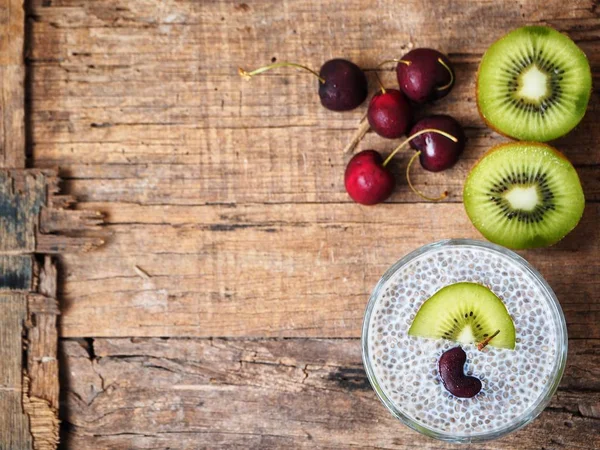 Chia seeds pudding with kiwi and cherries on old wooden background