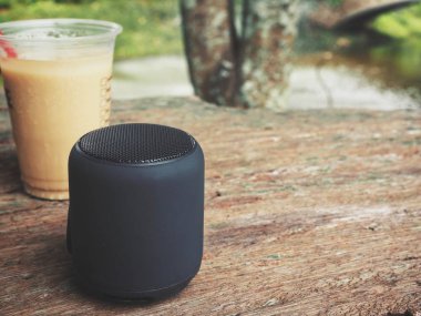 bluetooth hoparlör ahşap masanın üzerinde açık havada buzlu kahve cam ile yatan yakın çekim vurdu