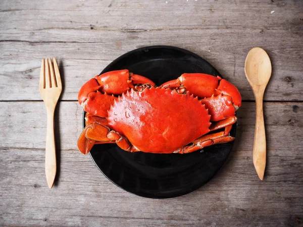 siyah plaka ve ahşap masa üzerinde çatal kaşıkla lezzetli taze yengeç üstten görünüm  