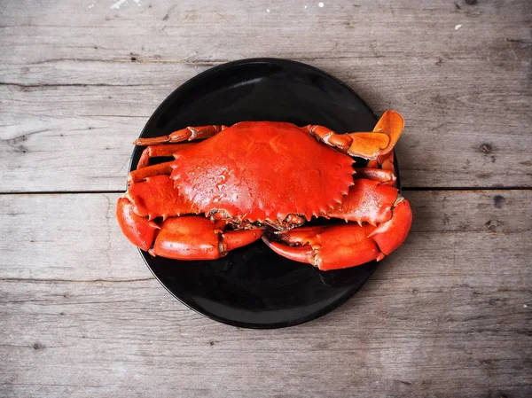 top view of delicious fresh crab on black plate on wooden table