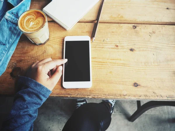 Жінка використовує смартфон з порожнім блокнотом і чашкою кави на офісному столі — стокове фото