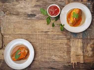 Eski ahşap arka plan üzerinde domates soslu beyaz tabaklarda konserve balık